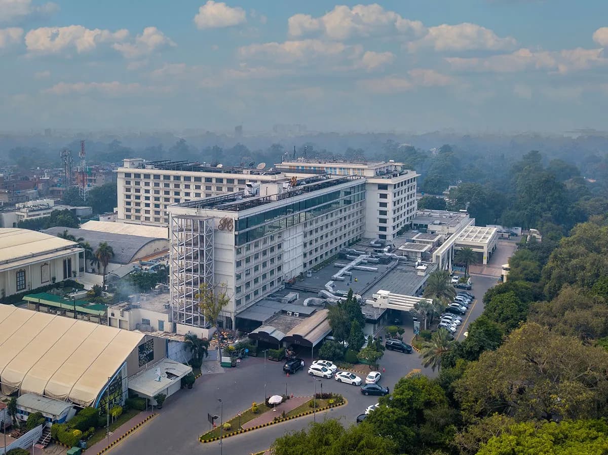 Aerial view of a city hotel complex surrounded by trees and low buildings